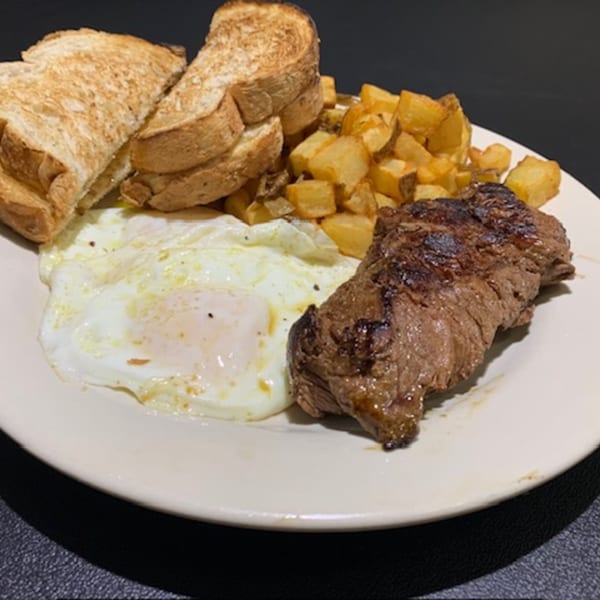 A diner breakfast plate with steak, fried eggs, home fries, and toast.