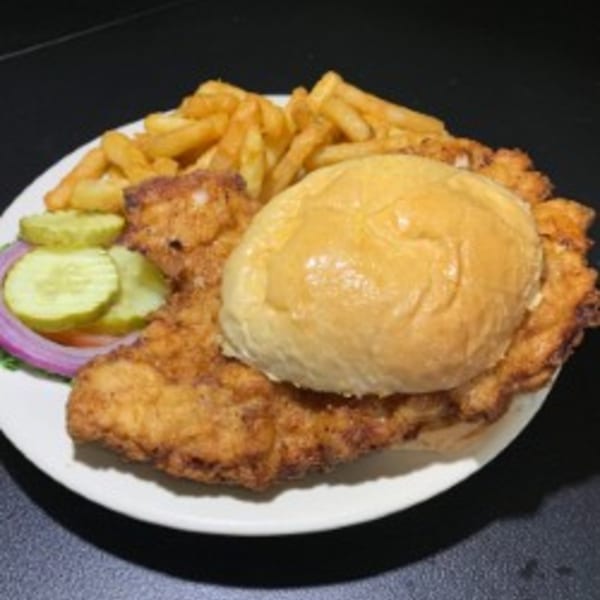 A crispy fried chicken sandwich with pickles, red onion, and a side of golden french fries.